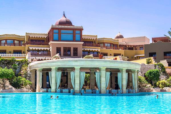 Eine Poollandschaft und ein Hotel im Hintergrund.